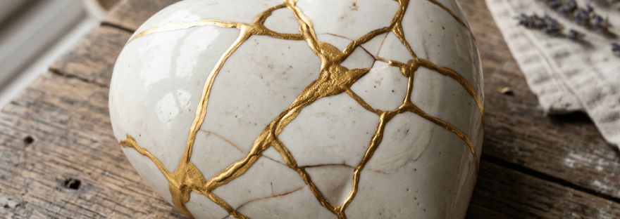 Ceramic heart sculpture with gold kintsugi repair lines on wooden table